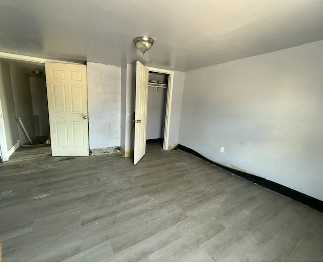 unfurnished bedroom featuring a closet, baseboards, and wood finished floors