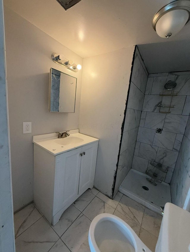 full bathroom with marble finish floor, a tile shower, and vanity