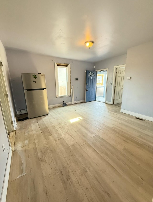 interior space featuring freestanding refrigerator, baseboards, visible vents, and light wood finished floors