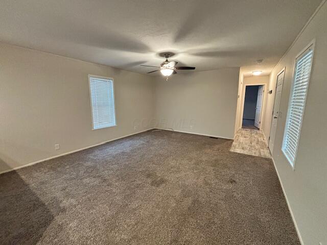 spare room with ceiling fan and dark carpet