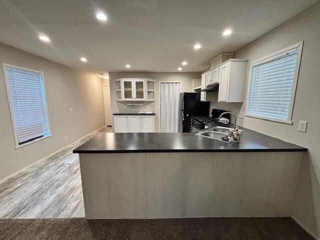 kitchen with a peninsula, dark countertops, open shelves, and recessed lighting