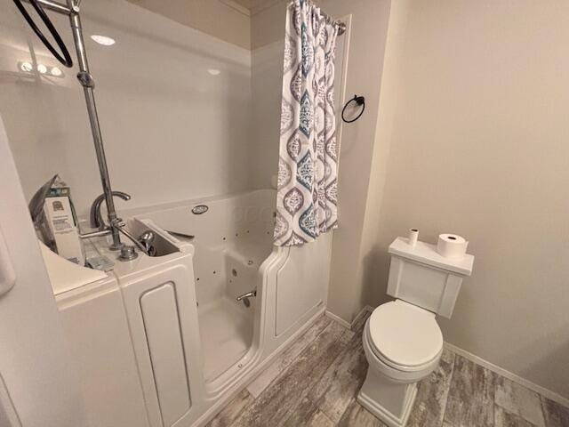 full bathroom featuring a jetted tub, baseboards, toilet, and wood finished floors