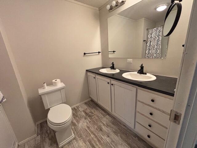 bathroom with double vanity, a sink, toilet, and wood finished floors