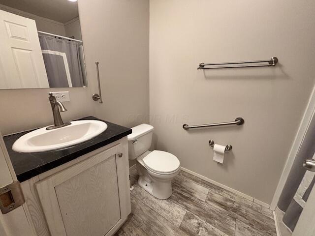 full bath featuring toilet, baseboards, wood finished floors, and vanity