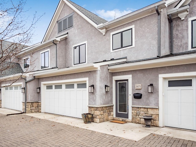 multi unit property featuring decorative driveway, stone siding, and stucco siding