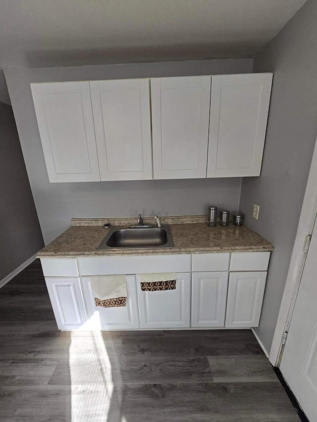 kitchen with a sink, baseboards, dark wood finished floors, and white cabinetry