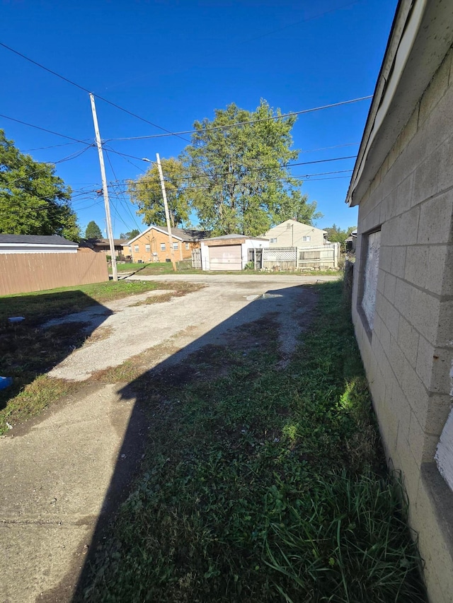 view of yard featuring fence, a garage, and driveway