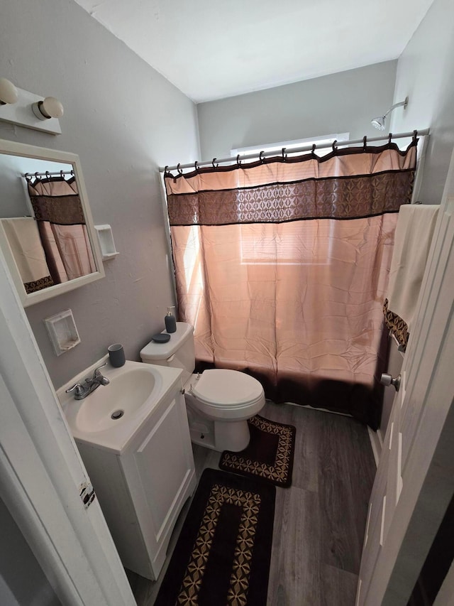 bathroom featuring toilet, vanity, shower / bath combo, and wood finished floors