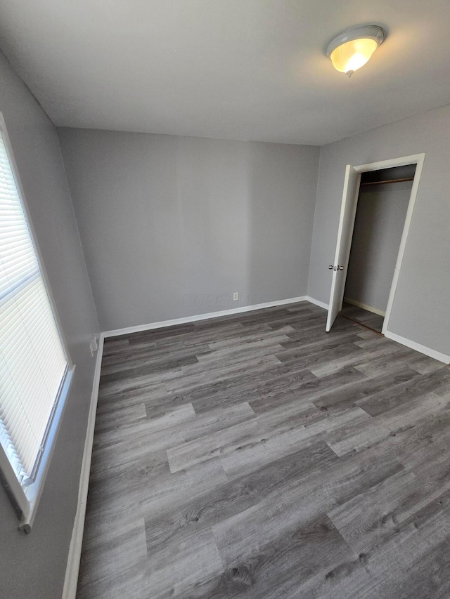 unfurnished bedroom with wood finished floors, baseboards, and a closet