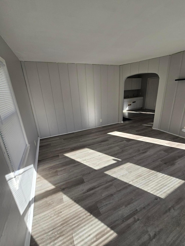 interior space featuring arched walkways and dark wood-type flooring