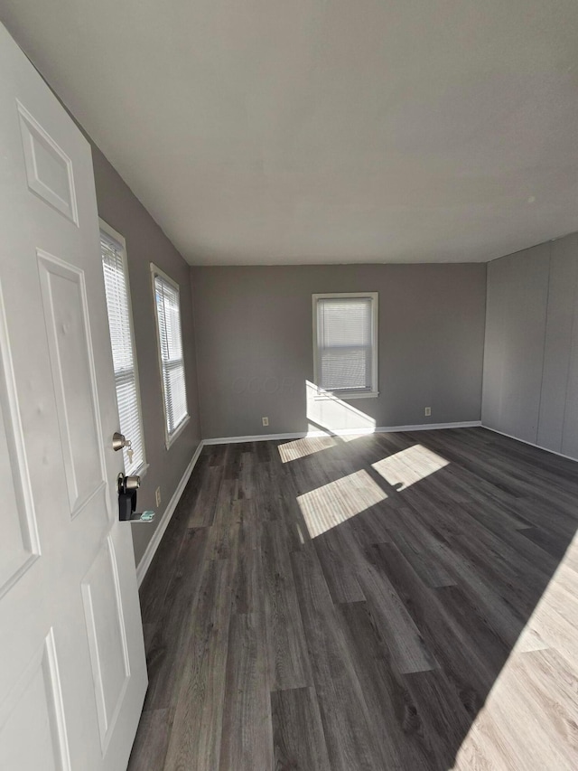 unfurnished room featuring baseboards and dark wood finished floors