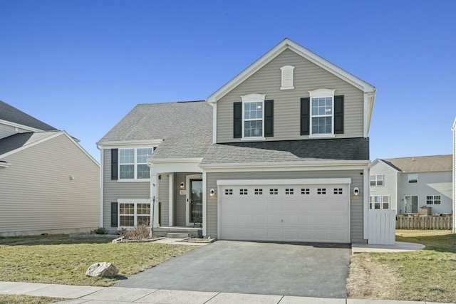 view of front of home with aphalt driveway, fence, roof with shingles, a front yard, and a garage