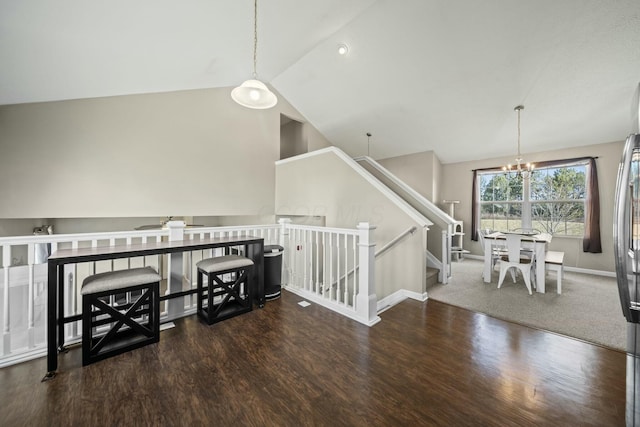 interior space with an inviting chandelier, vaulted ceiling, wood finished floors, and baseboards