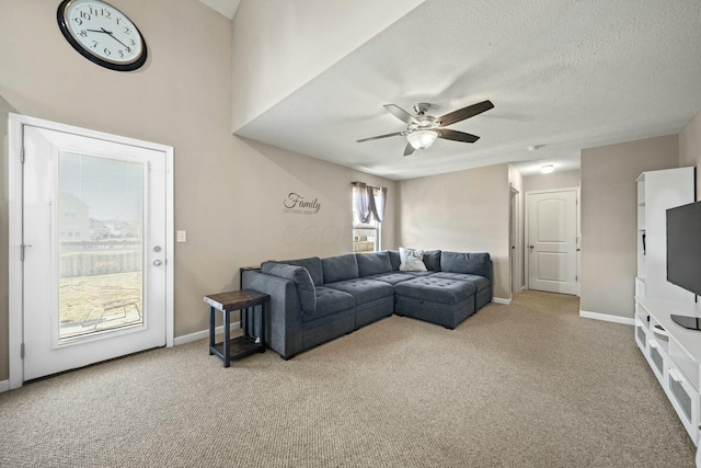 carpeted living room with ceiling fan, baseboards, and a textured ceiling