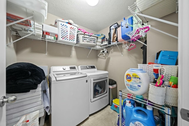 laundry area featuring a textured ceiling, laundry area, light tile patterned flooring, and washer and clothes dryer