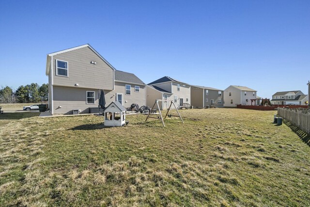 back of property featuring a residential view, a yard, and fence