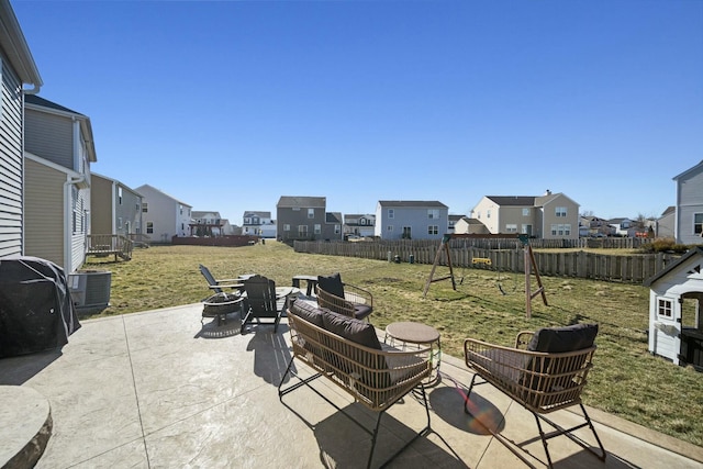 view of patio / terrace with an outdoor living space with a fire pit, central AC unit, fence, and a residential view