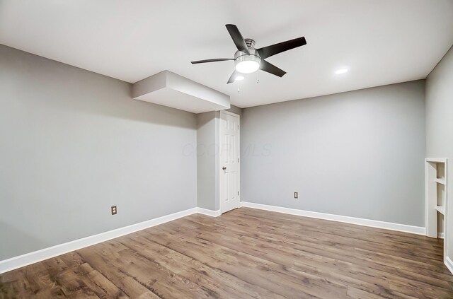 unfurnished room with wood finished floors, a ceiling fan, and baseboards