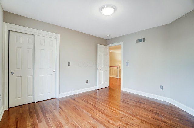 unfurnished bedroom with light wood-type flooring, a closet, visible vents, and baseboards