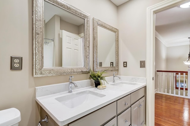 bathroom with crown molding, a sink, toilet, and wood finished floors