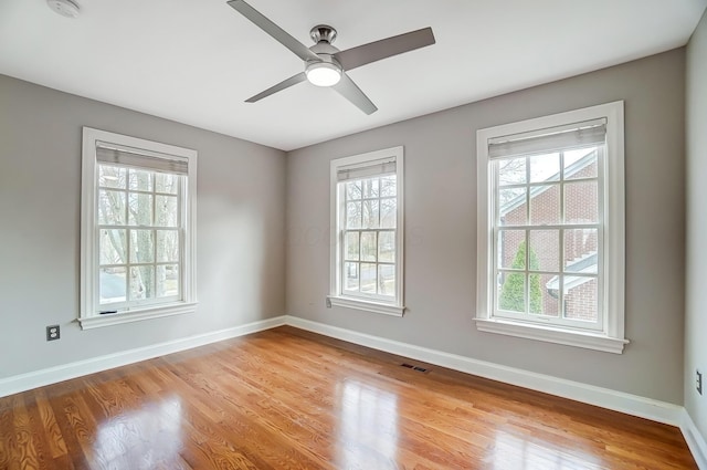 empty room featuring ceiling fan, light wood-style flooring, visible vents, and baseboards