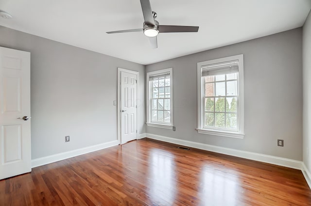 unfurnished room featuring ceiling fan, wood finished floors, visible vents, and baseboards