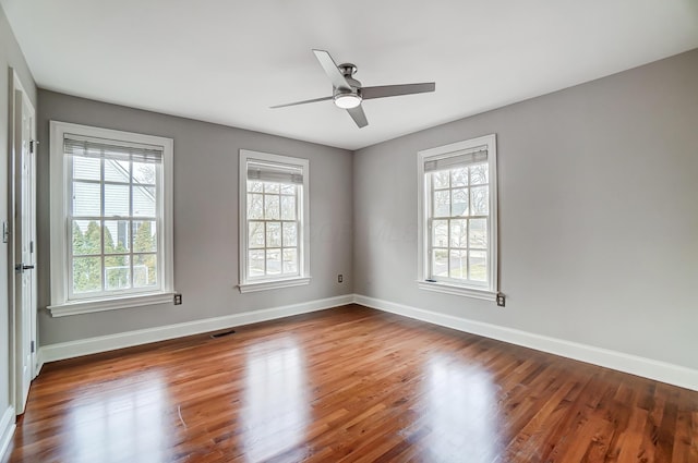 empty room featuring plenty of natural light, visible vents, and baseboards