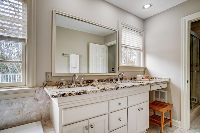 full bath featuring a healthy amount of sunlight, a sink, and a shower with door