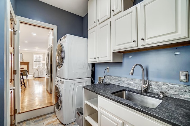 laundry area featuring cabinet space, a sink, and stacked washing maching and dryer