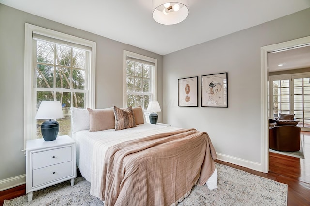 bedroom with multiple windows, baseboards, and wood finished floors