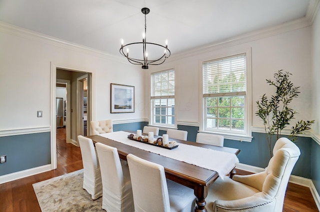 dining space with ornamental molding, a chandelier, baseboards, and wood finished floors