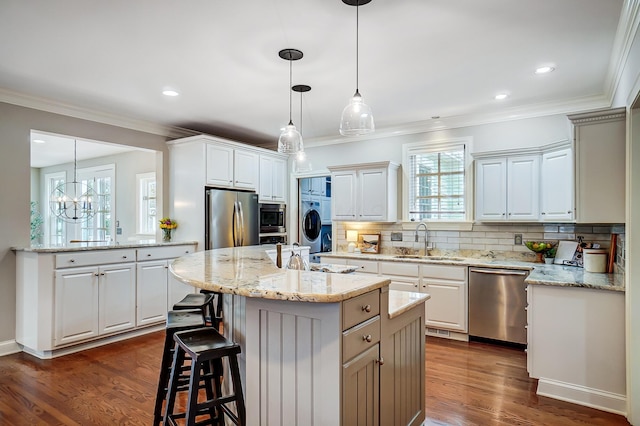 kitchen featuring a center island, decorative backsplash, appliances with stainless steel finishes, ornamental molding, and a sink