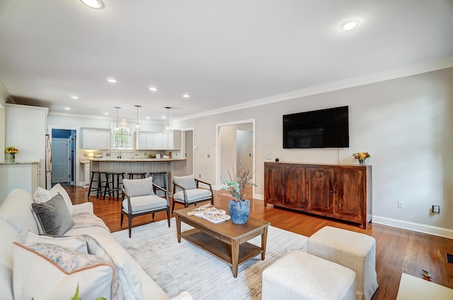 living room featuring light wood-style flooring, ornamental molding, baseboards, and recessed lighting