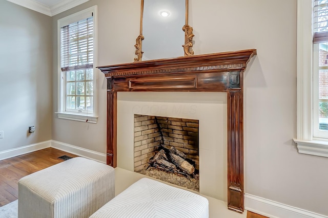 bedroom featuring baseboards, visible vents, wood finished floors, crown molding, and a fireplace