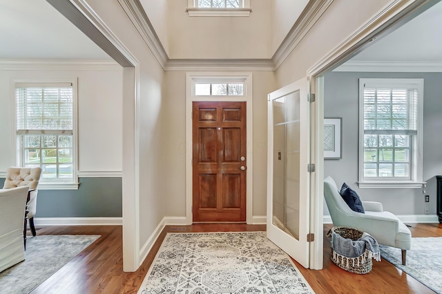 foyer featuring baseboards, wood finished floors, and crown molding