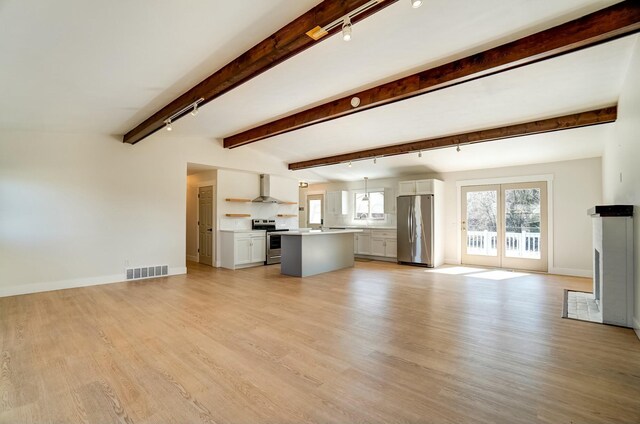 unfurnished living room with light wood-type flooring, visible vents, baseboards, and beam ceiling