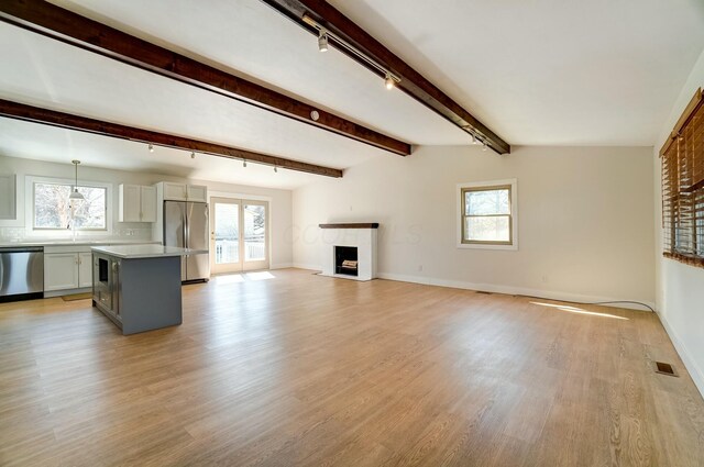 unfurnished living room featuring visible vents, beam ceiling, light wood-style flooring, a fireplace, and french doors