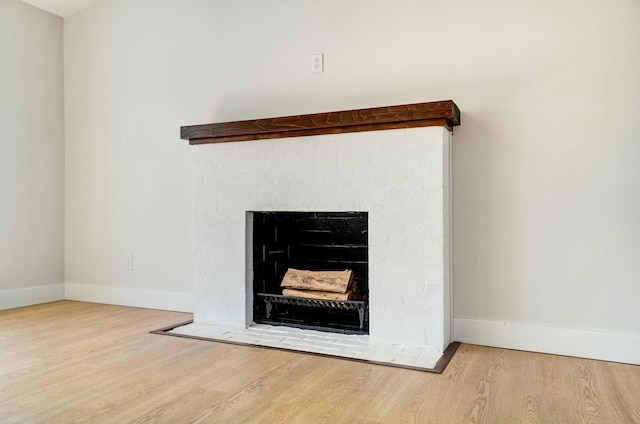 room details featuring a fireplace with flush hearth, wood finished floors, and baseboards