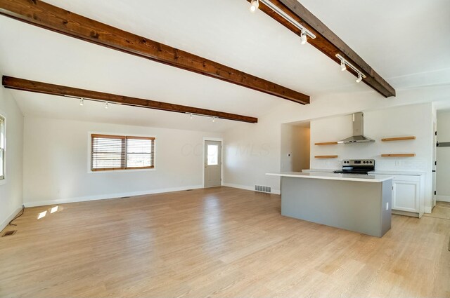 kitchen featuring beamed ceiling, stainless steel range with electric stovetop, light wood-style flooring, open shelves, and wall chimney exhaust hood