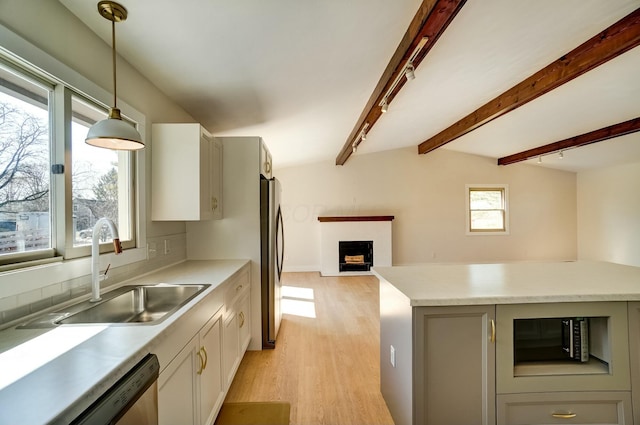 kitchen with a fireplace, stainless steel appliances, a sink, pendant lighting, and open floor plan