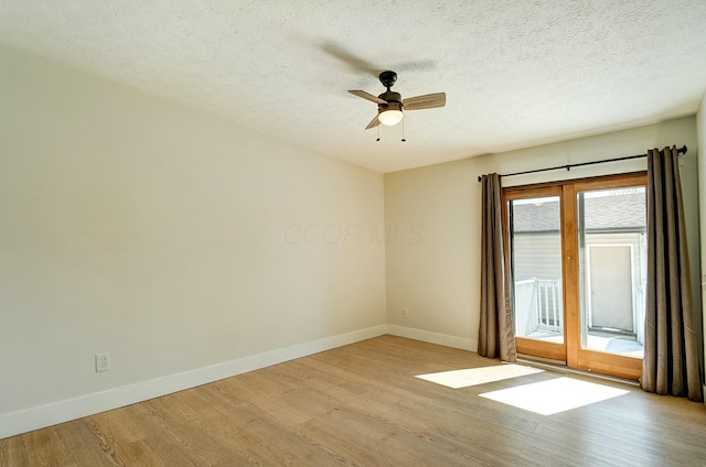 empty room with baseboards, a textured ceiling, wood finished floors, and a ceiling fan