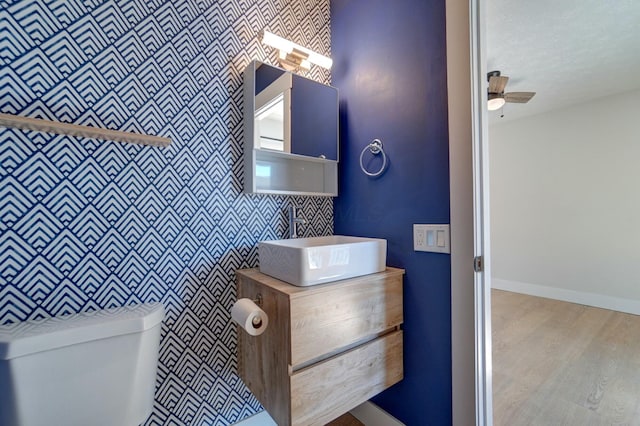 bathroom with vanity, wood finished floors, baseboards, ceiling fan, and toilet