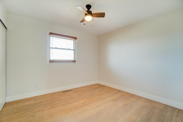 spare room featuring visible vents, baseboards, wood finished floors, and a ceiling fan