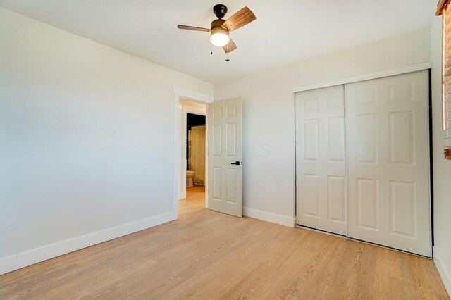 unfurnished bedroom featuring ceiling fan, a closet, baseboards, and light wood-style flooring