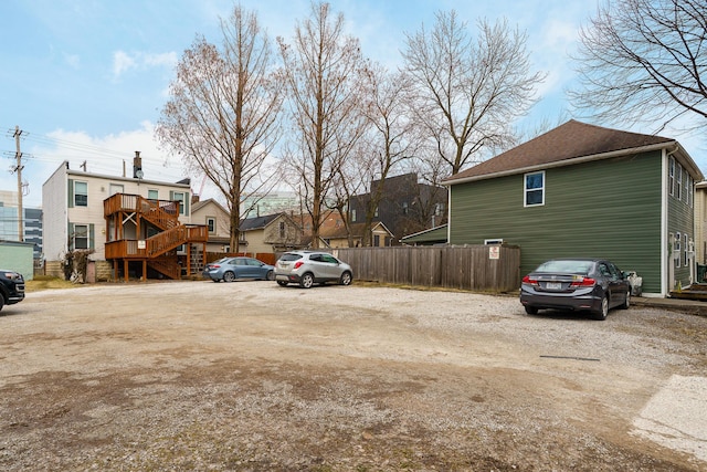 view of parking featuring fence and stairway