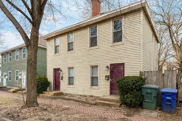 colonial-style house with a chimney and fence