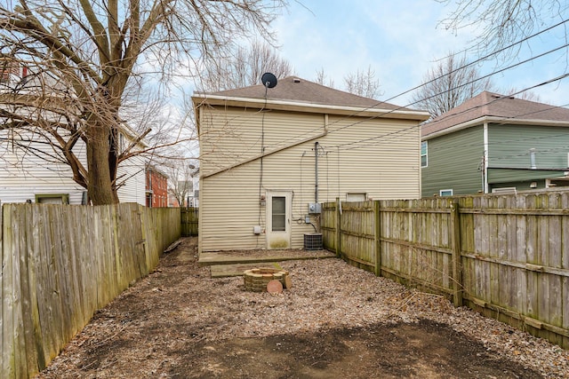 rear view of property featuring an outdoor fire pit and a fenced backyard