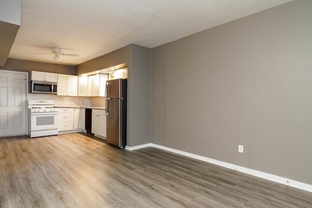 kitchen with stainless steel appliances, tasteful backsplash, white cabinets, wood finished floors, and baseboards