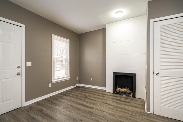 unfurnished living room with dark wood-style floors, a fireplace, and baseboards