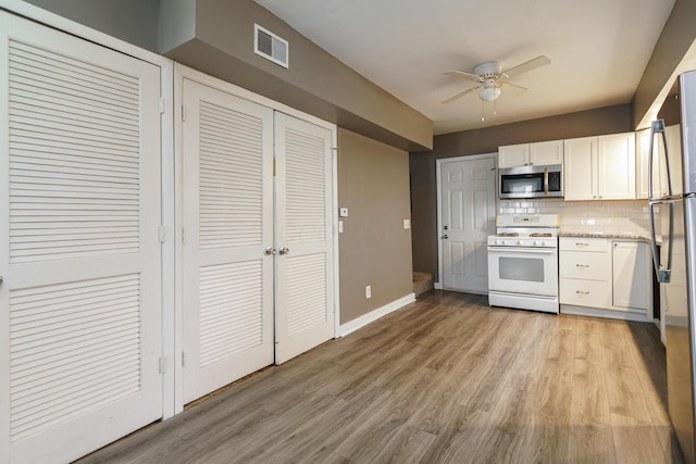 kitchen with light wood-style flooring, stainless steel appliances, visible vents, white cabinets, and tasteful backsplash